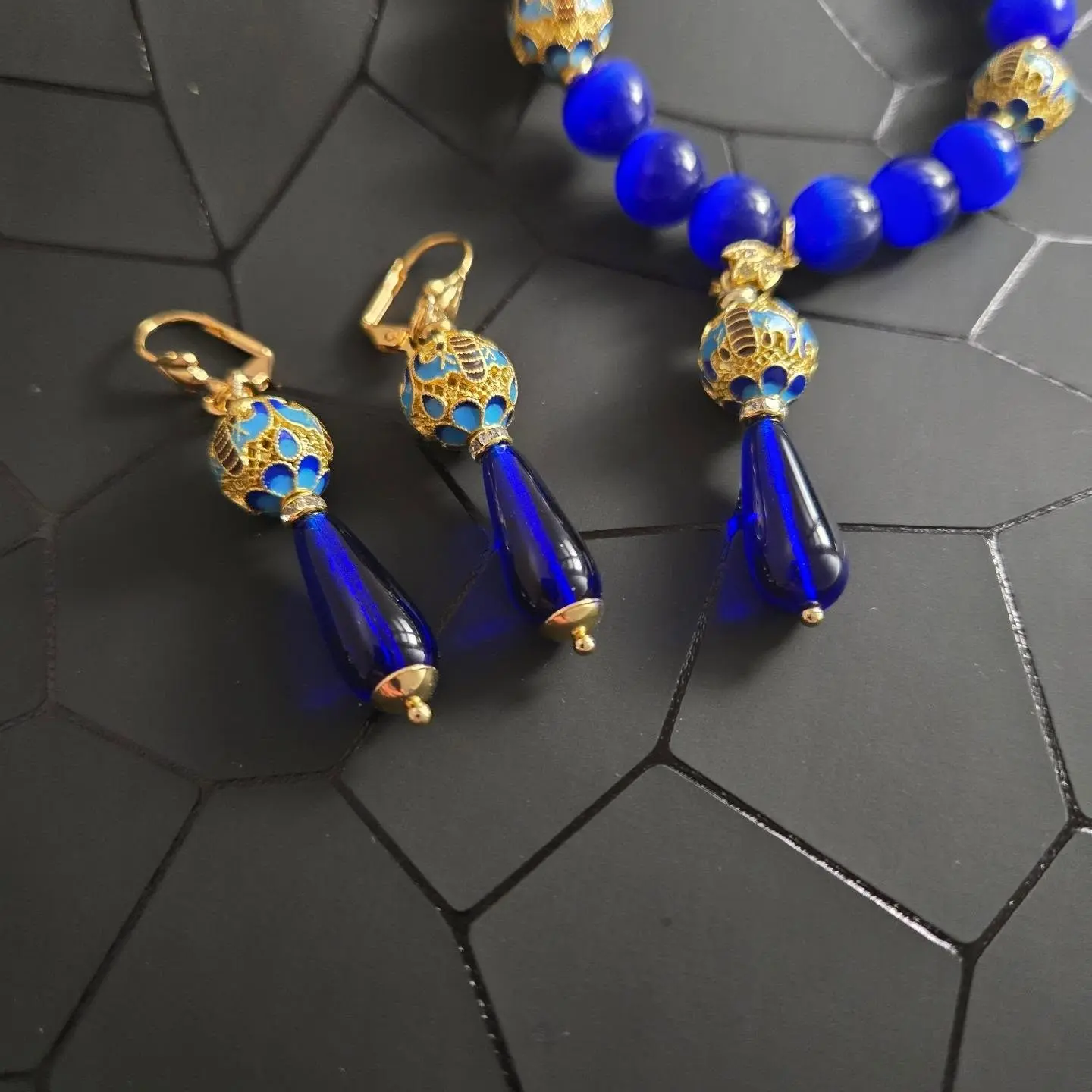 a royal blue and gold jewelry set, including a bracelet and a pair of earrings